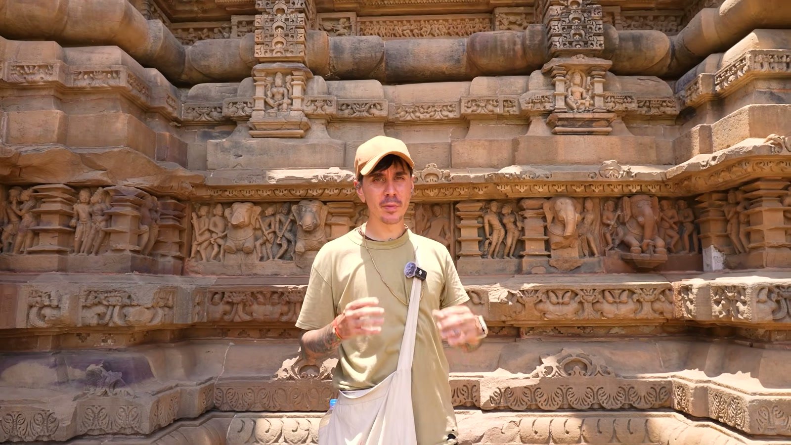 Dakota Wint standing before a carved temple frieze in Odisha, India, examining the sculptures.