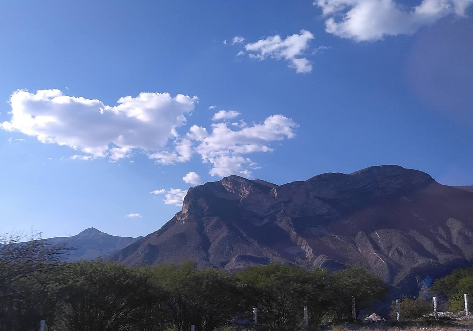 A dry, folded highland landscape of the Mixteca Alta in Oaxaca under a wide sky.