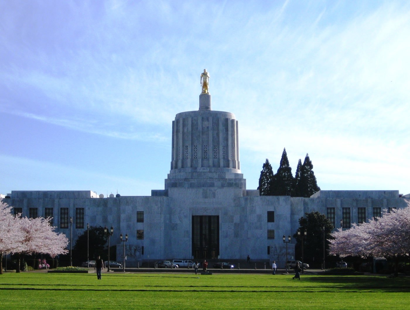 The Oregon State Capitol building with its gilded pioneer statue, framed by cherry blossom.